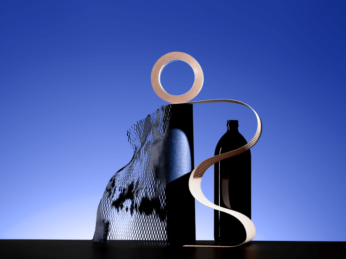 A visually striking abstract arrangement featuring a tape roll, corrugated paper, mesh material, and a bottle, set against a blue gradient background. The objects are creatively positioned to form an artistic display with bold contrasts and geometric forms.