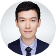 Portrait headshot of a professionally dressed person in a suit and tie, facing the camera and smiling gently, on a white background.