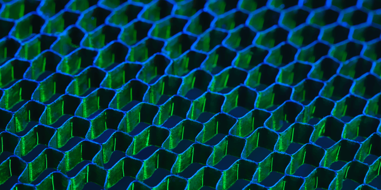 Close-up image of a blue and green hexagonal honeycomb pattern grid, showing geometric texture and light reflections.